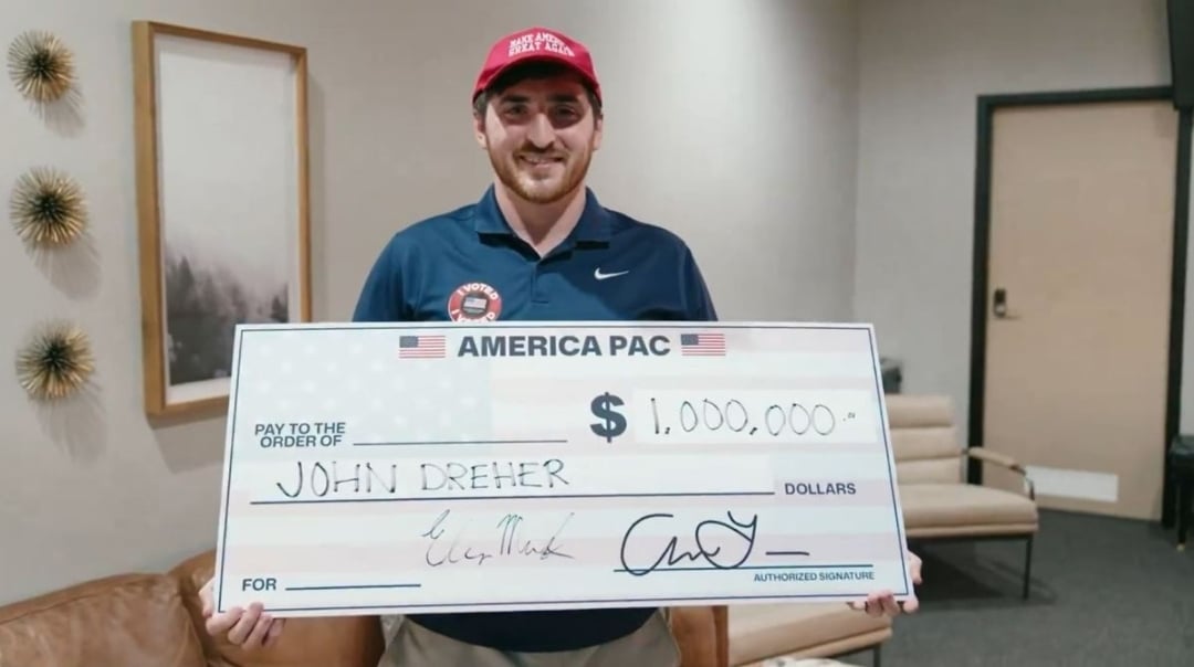 Guy holding a giant winner's check with his name, John Dreher, where the amount should be. 