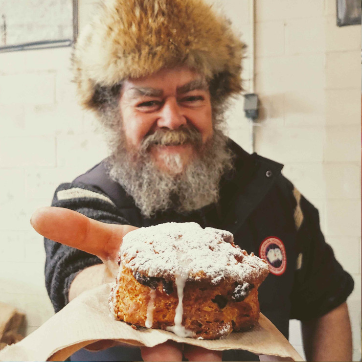 a scruffy looking man holding a cinnamon up to the camera