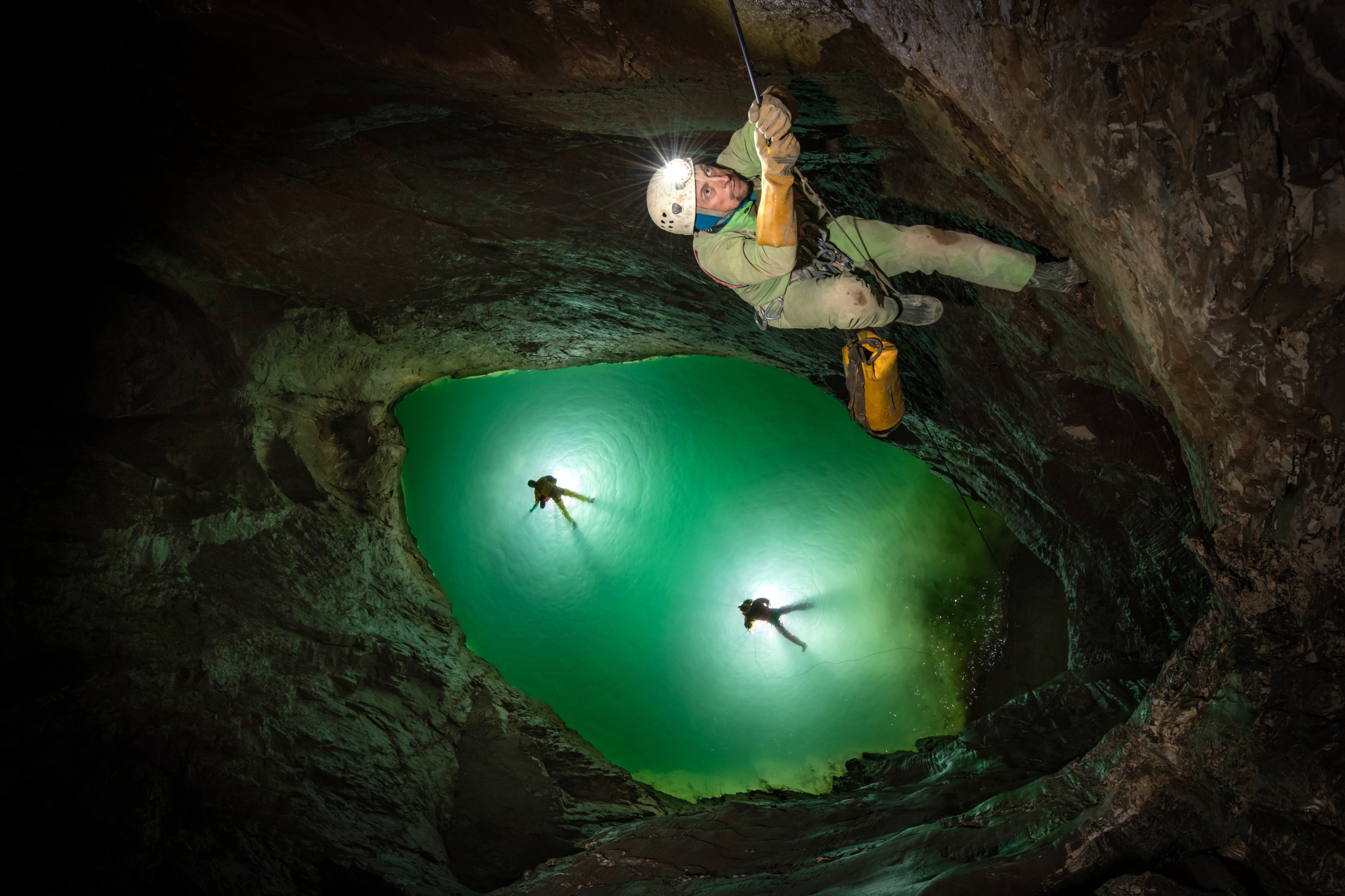 The lowest point in the cave. The siphon. Up until this expedition, this siphon is undived and nobody knows what lies beneath. This is the deepest point in the deepest cave in the world! At -2212m underground. Leader Pavel Demidov climbs up the rope above two swimmers swimming in the sump pool 12m below. A strong current coming up from the left hand side suggests that there might be a flooded passage below the surface, but up to now, who knows? During the flood pulse that cave down through the cave a week after this photograph was taken, all of this completley filled up with water, right up to the roof.